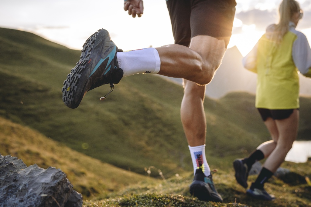 Traillauf von zwei Personen bei Sonnenaufgang in den Bergen